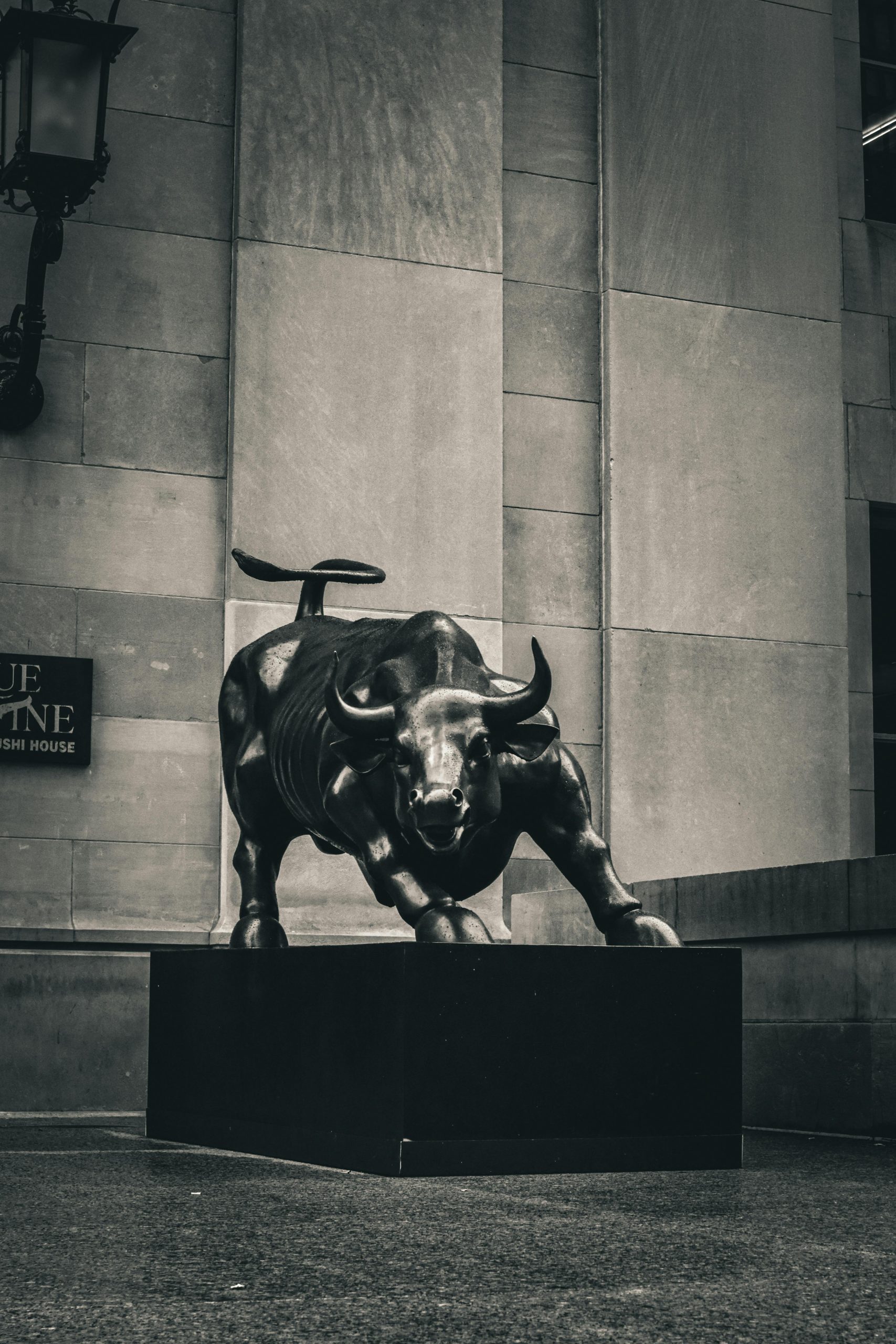 Black and white image of the Charging Bull statue in a cityscape, symbolizing strength and finance.